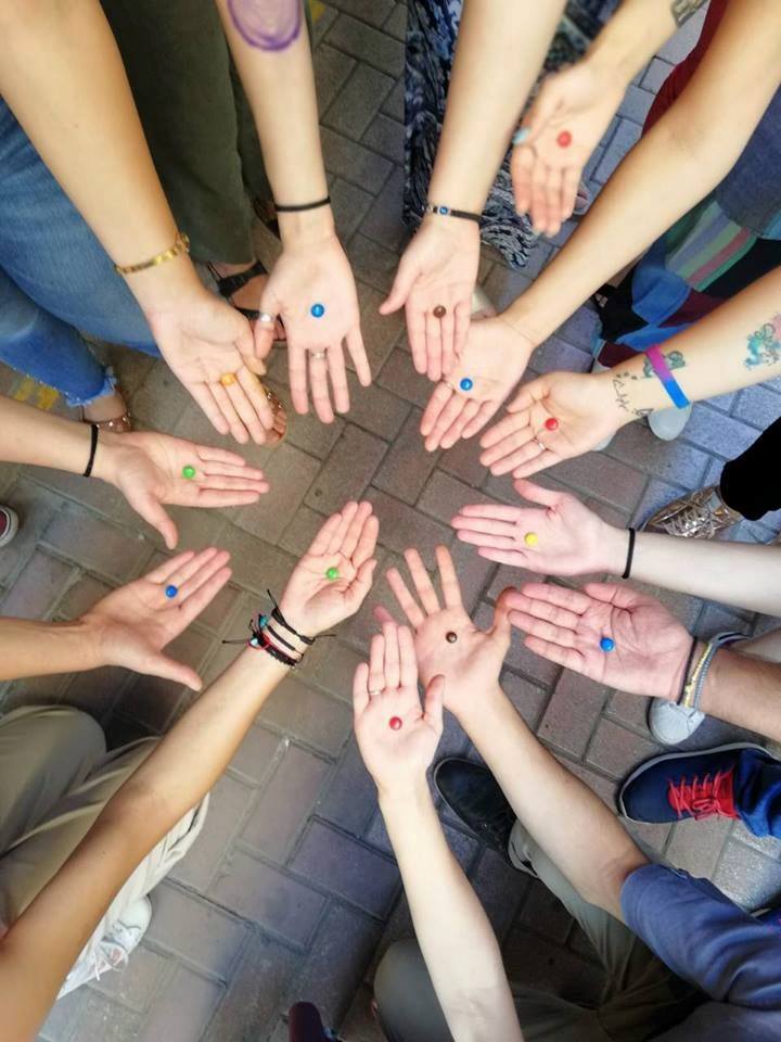 Hands of young people standing in circle. They are each holding 1 m&m candy.